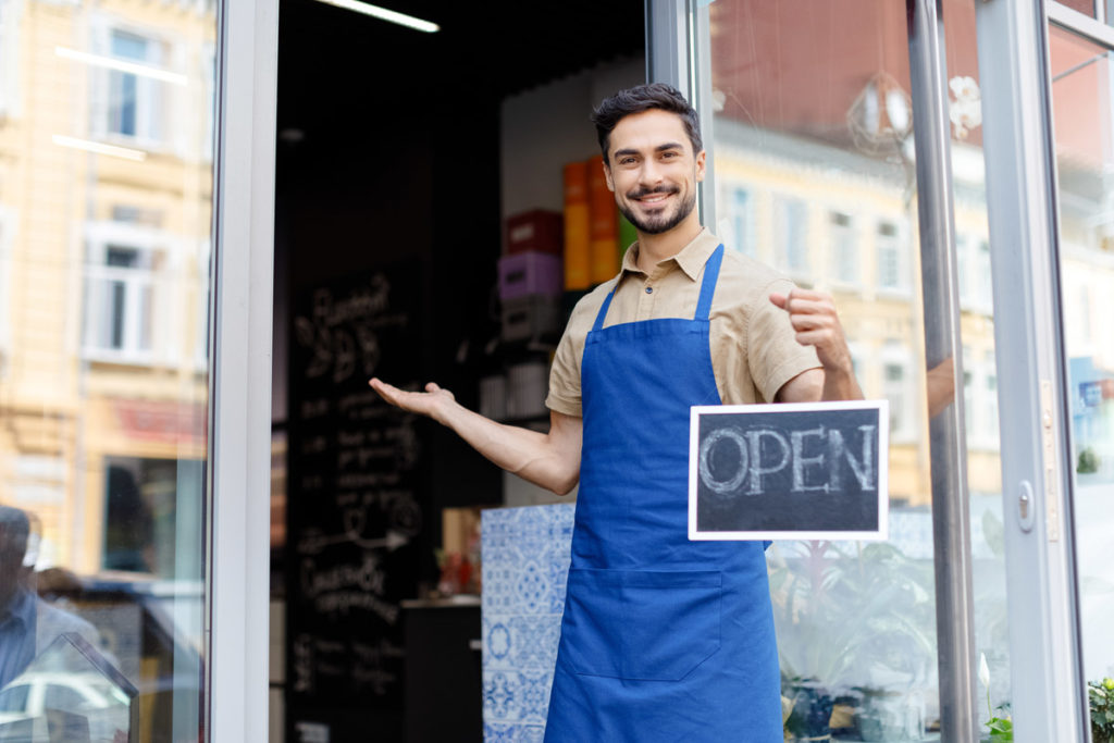 Commercial insurance in Dallas, TX, shopkeeper holding open sign